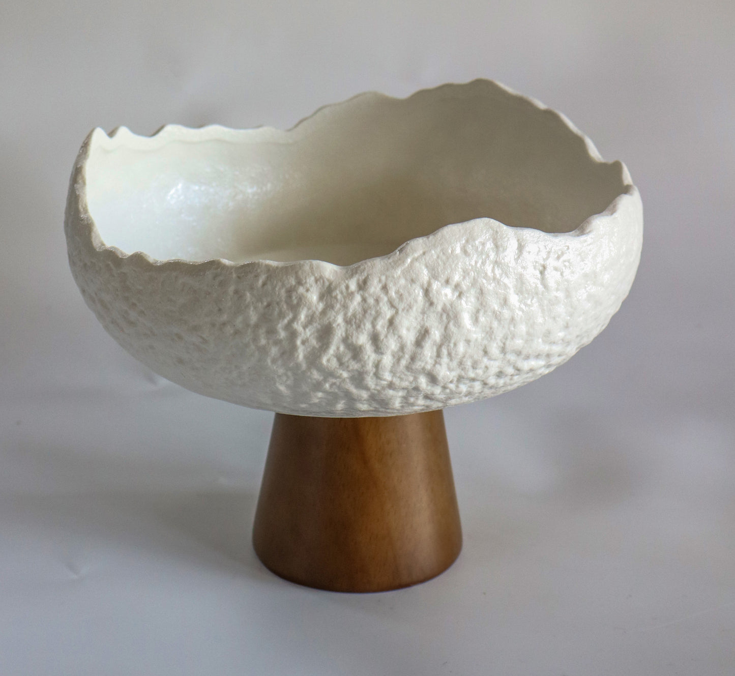 קערה לבנה מחוספסת על רגל עץ קטנה וגבוהה
